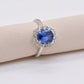 Ring with a blue gemstone and diamond halo on a beige cushion