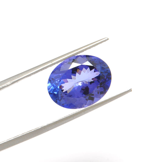 Close-up of a SAR Gems natural tanzanite gemstone, 7.65 carats, faceted oval cut, 11.5x14.5mm, showcasing violet-blue color and brilliant clarity.