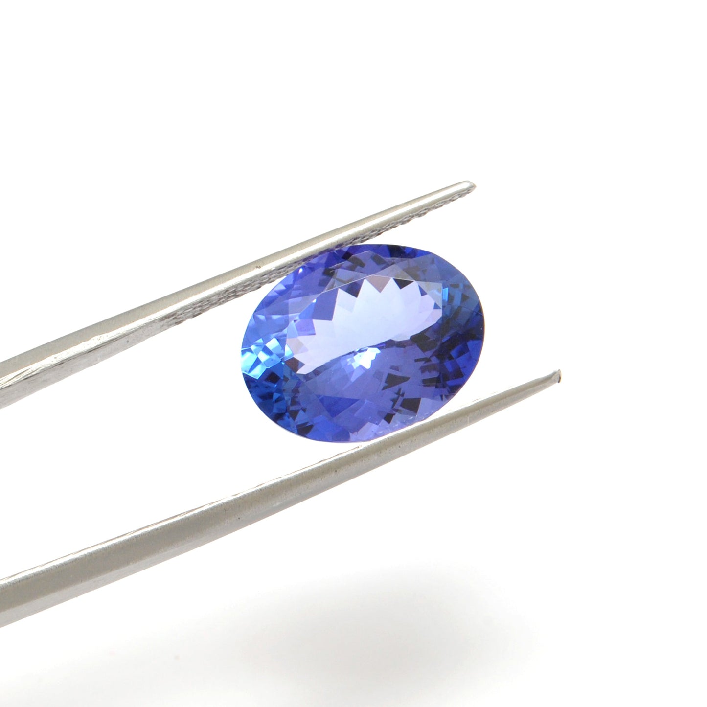 Close-up of a SAR Gems natural tanzanite gemstone, 7.65 carats, faceted oval cut, 11.5x14.5mm, showcasing violet-blue color and brilliant clarity.