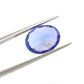 Close-up of a SAR Gems natural tanzanite gemstone, 7.65 carats, faceted oval cut, 11.5x14.5mm, showcasing violet-blue color and brilliant clarity.