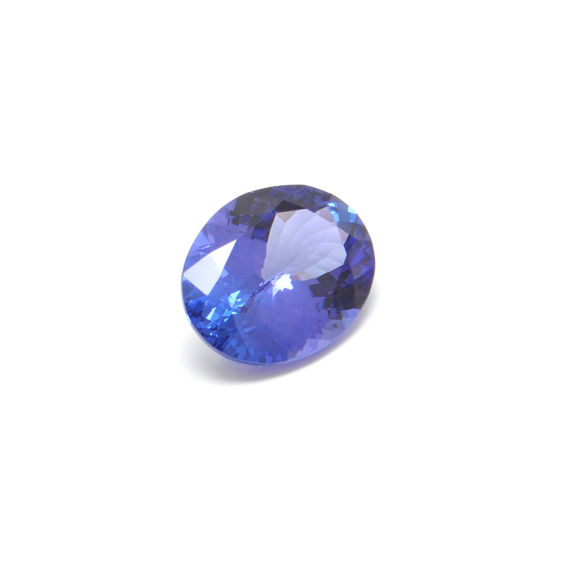 Close-up of a SAR Gems natural tanzanite gemstone, 7.65 carats, faceted oval cut, 11.5x14.5mm, showcasing violet-blue color and brilliant clarity.