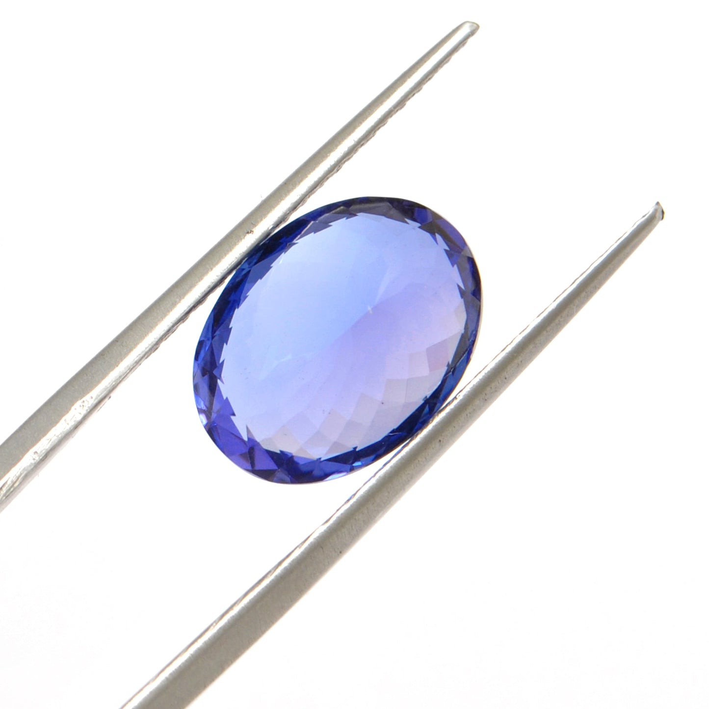 Close-up of a SAR Gems natural tanzanite gemstone, 6.25 carats, faceted oval cut, 6x10mm, showcasing violet-blue color and brilliant clarity