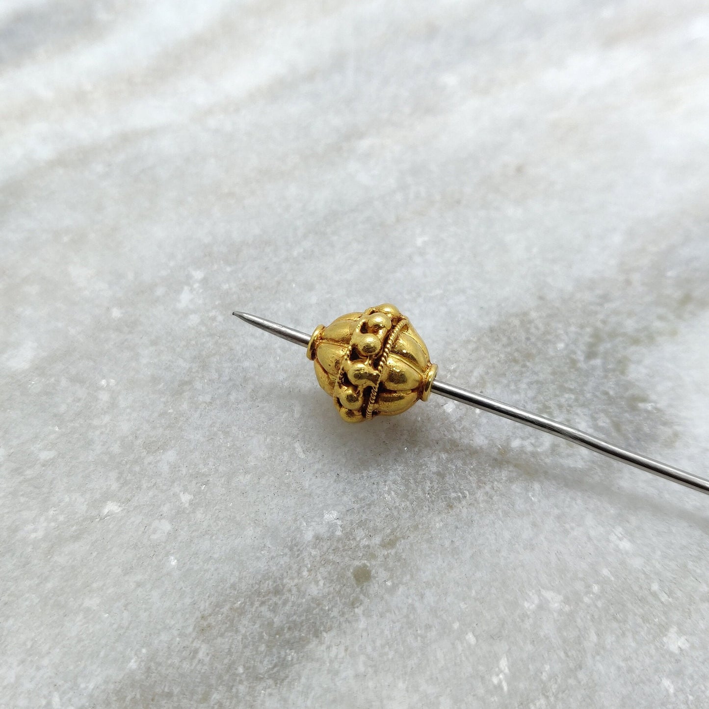 Close-up of solid 18K gold round spacer bead showing smooth polished surface
