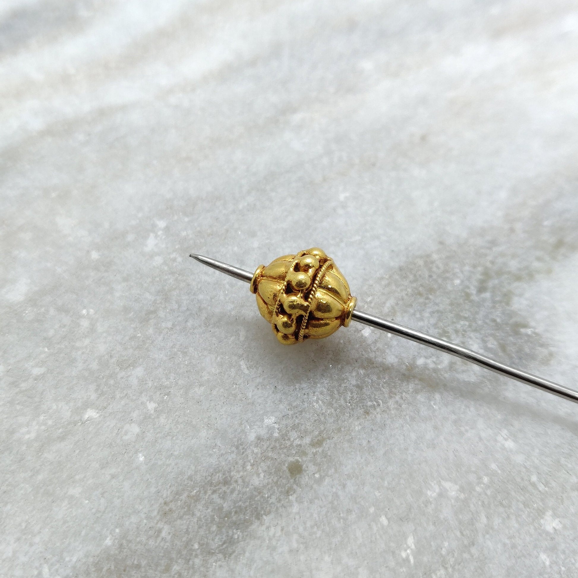 Close-up of solid 18K gold round spacer bead showing smooth polished surface